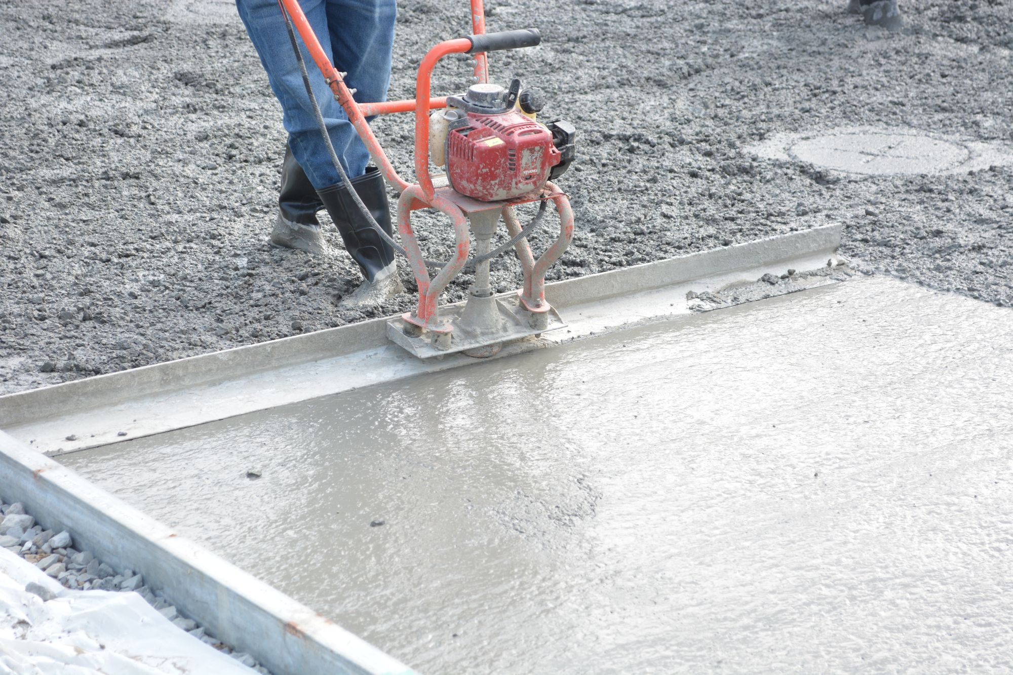 A power screed levelling a freshly poured concrete slab.