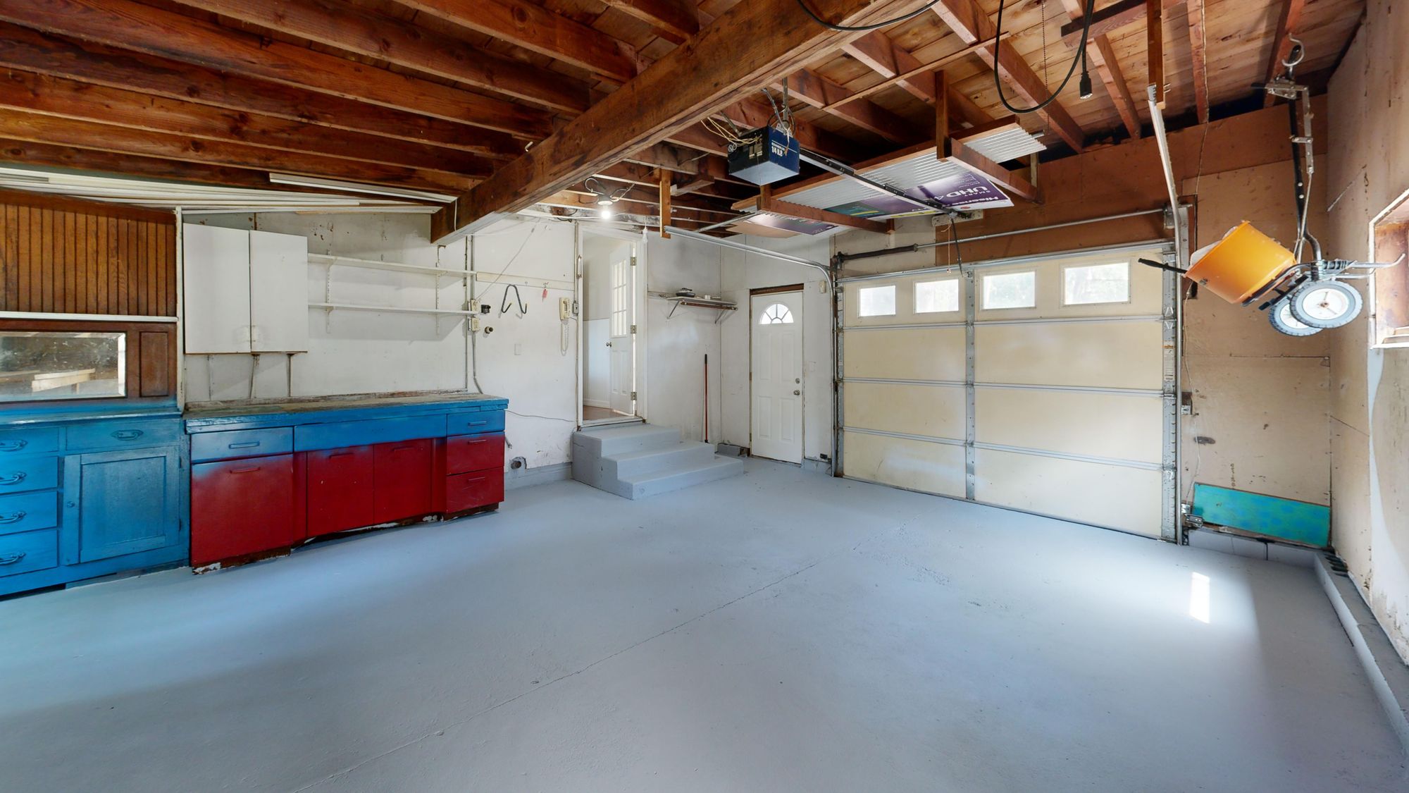 A residential garage with a coated concrete floor and painted cabinetry.
