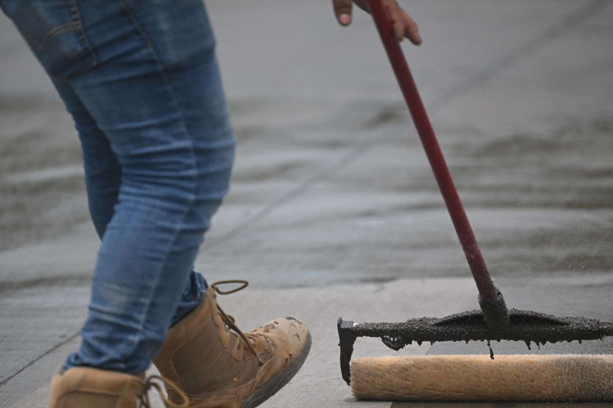 A squeegee spreading sealer across concrete.