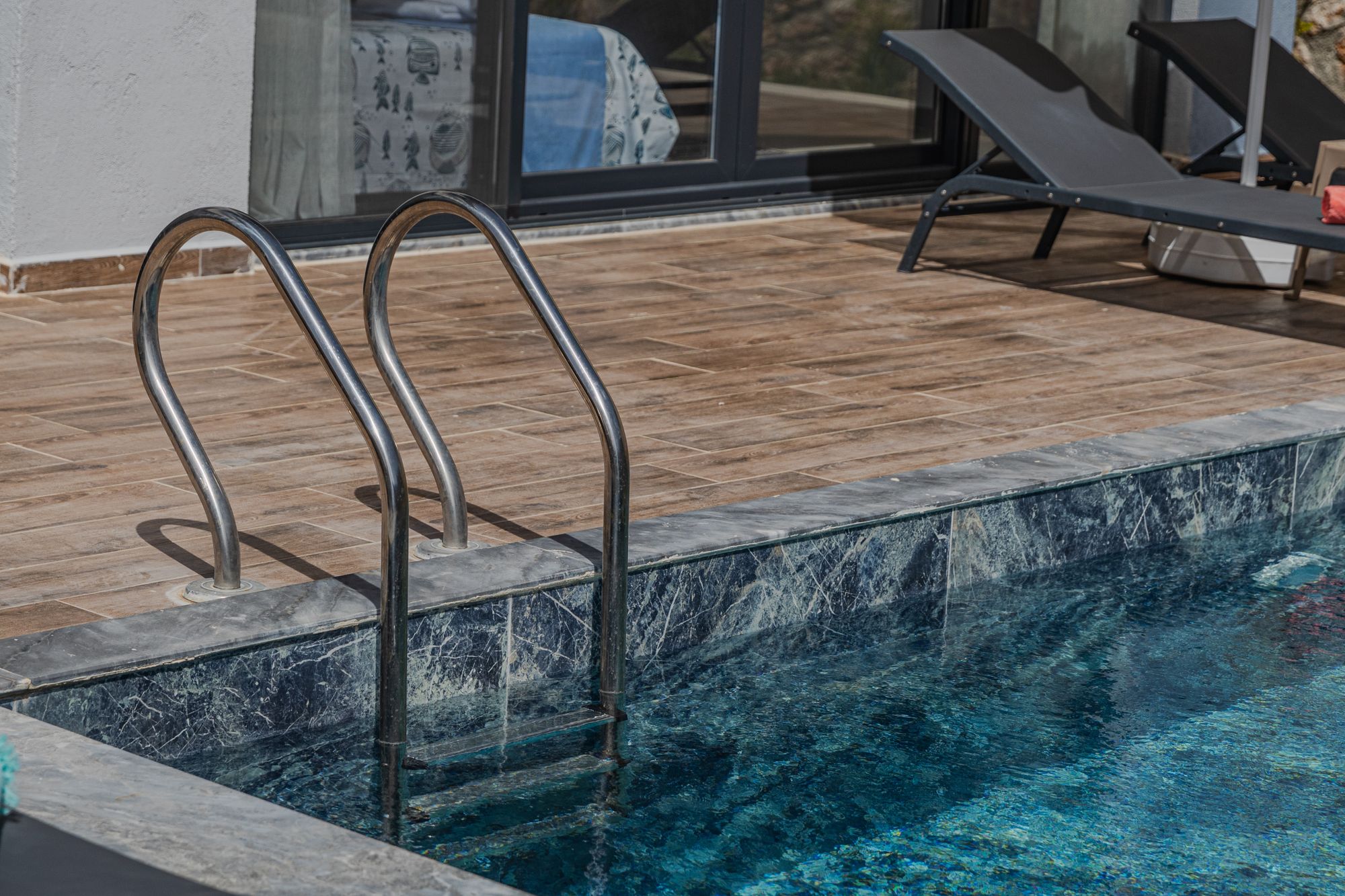 Veined marble coping at the edge of a swimming pool.